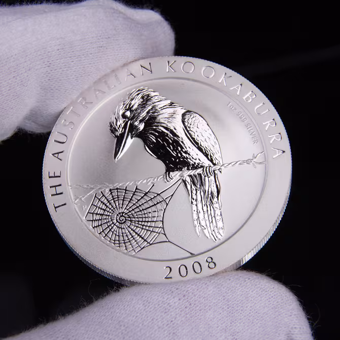 Perth Mint Australian Kookaburra Silbermuenze 1 oz 2008 Vorderseite Kookaburra Spinnennetz 2008 in weissen Handschuhen